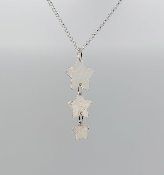 Silver star-shaped pendant necklace on a gray background