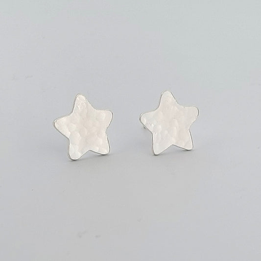 Star-shaped silver earrings on a light gray background