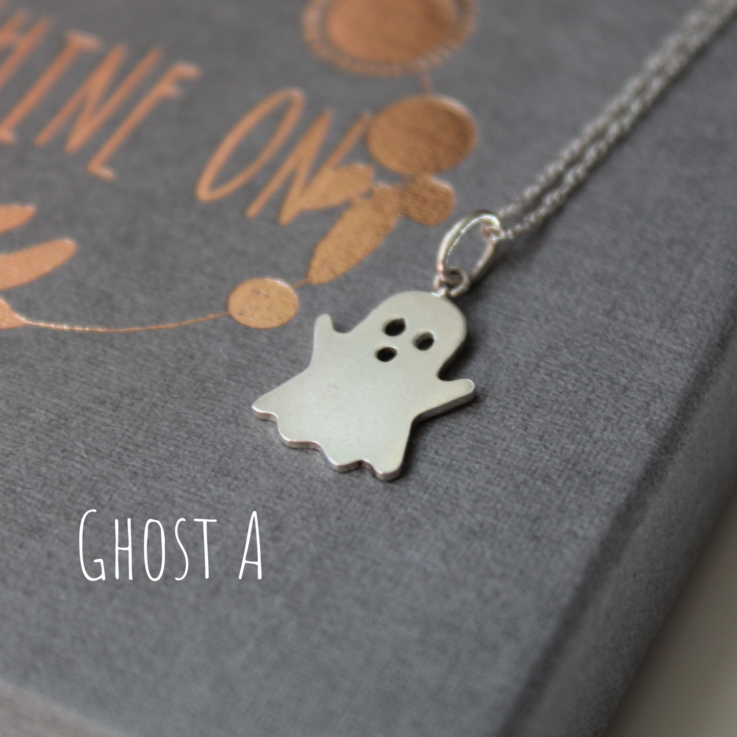 Sterling Silver Ghost Necklace, laying on a grey gift box, handmade by Shine On