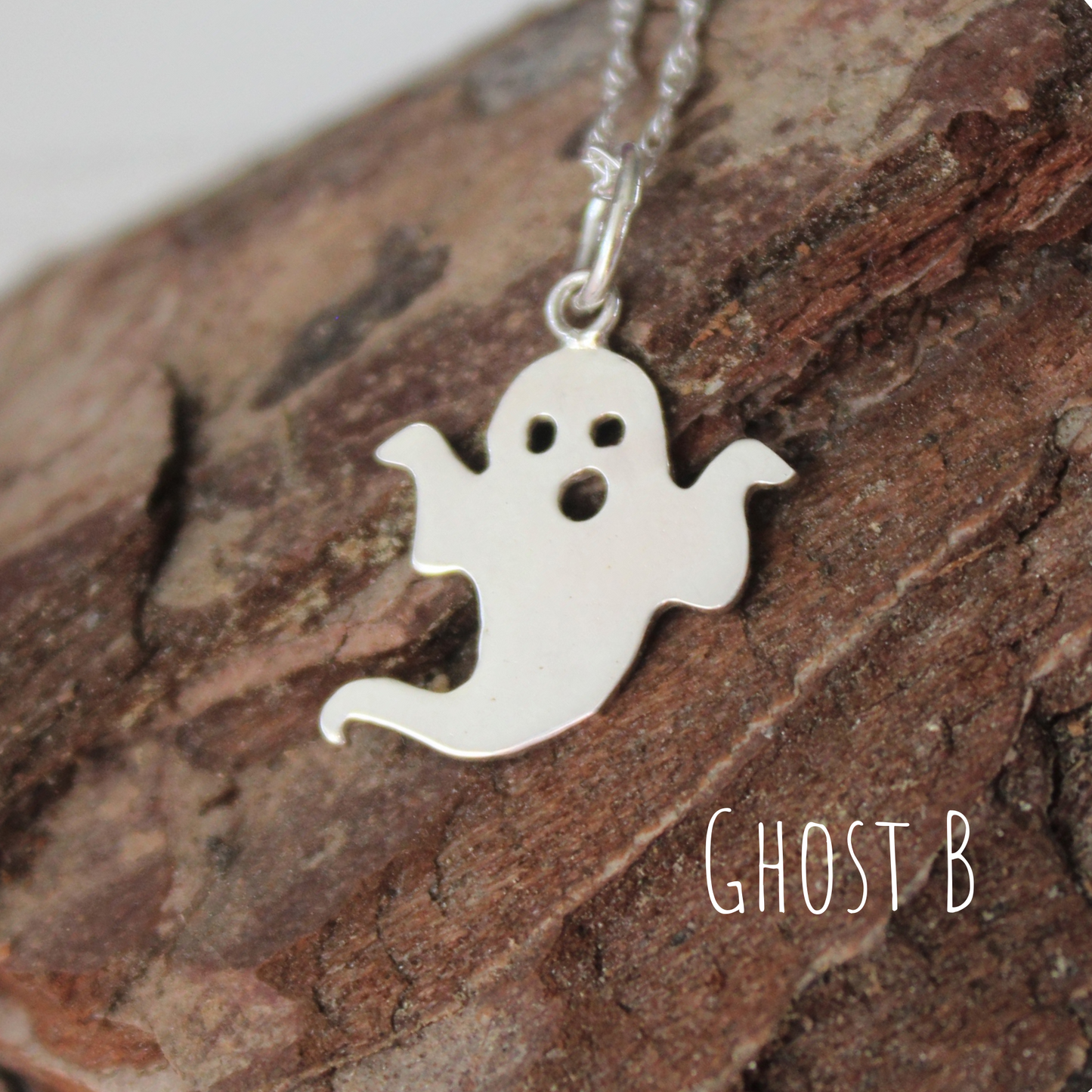 Sterling Silver Ghost Necklace, laying on a piece of wood, handmade by Shine On