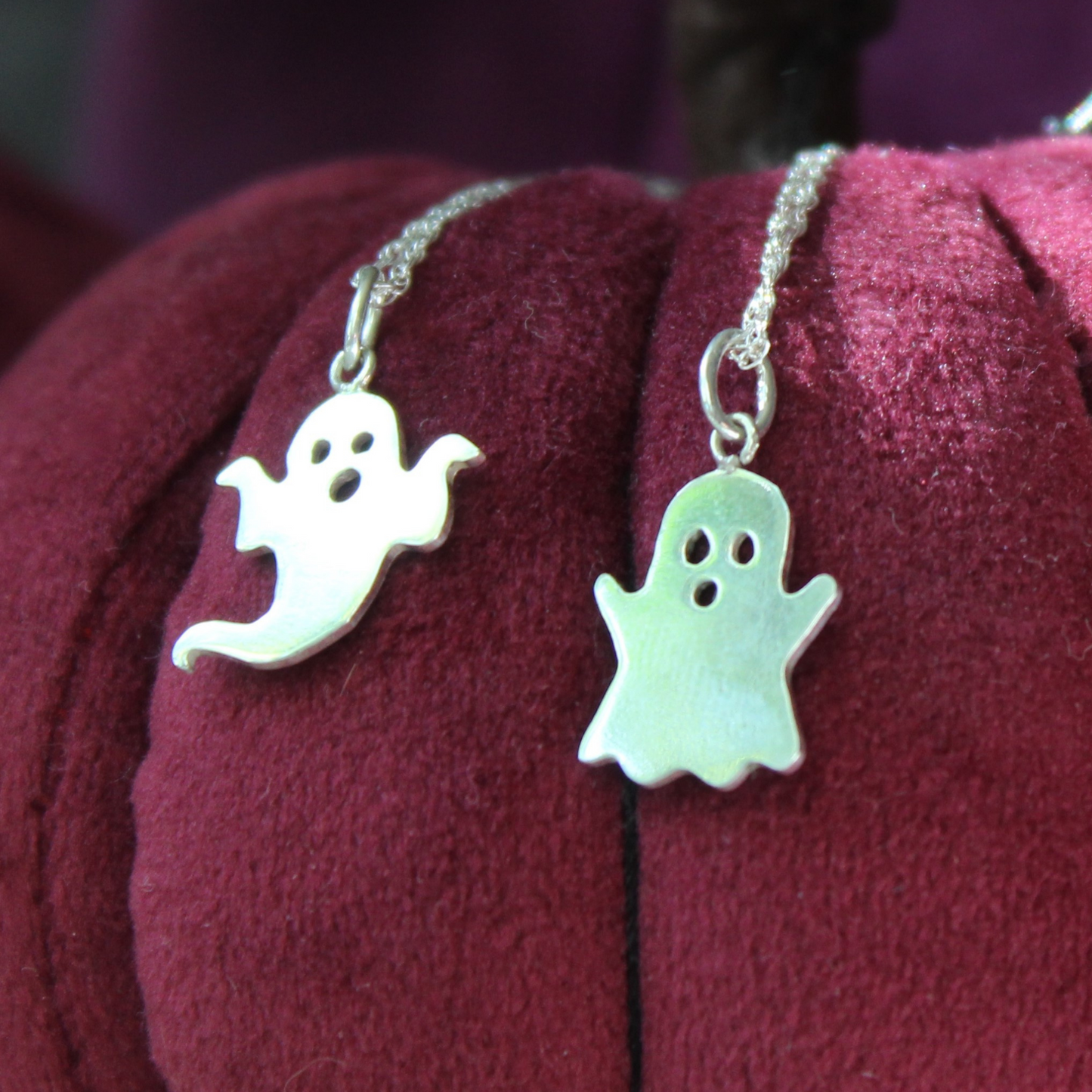 Sterling Silver Ghost Necklaces, resting on a burgundy plush pumpkin, handmade by Shine On