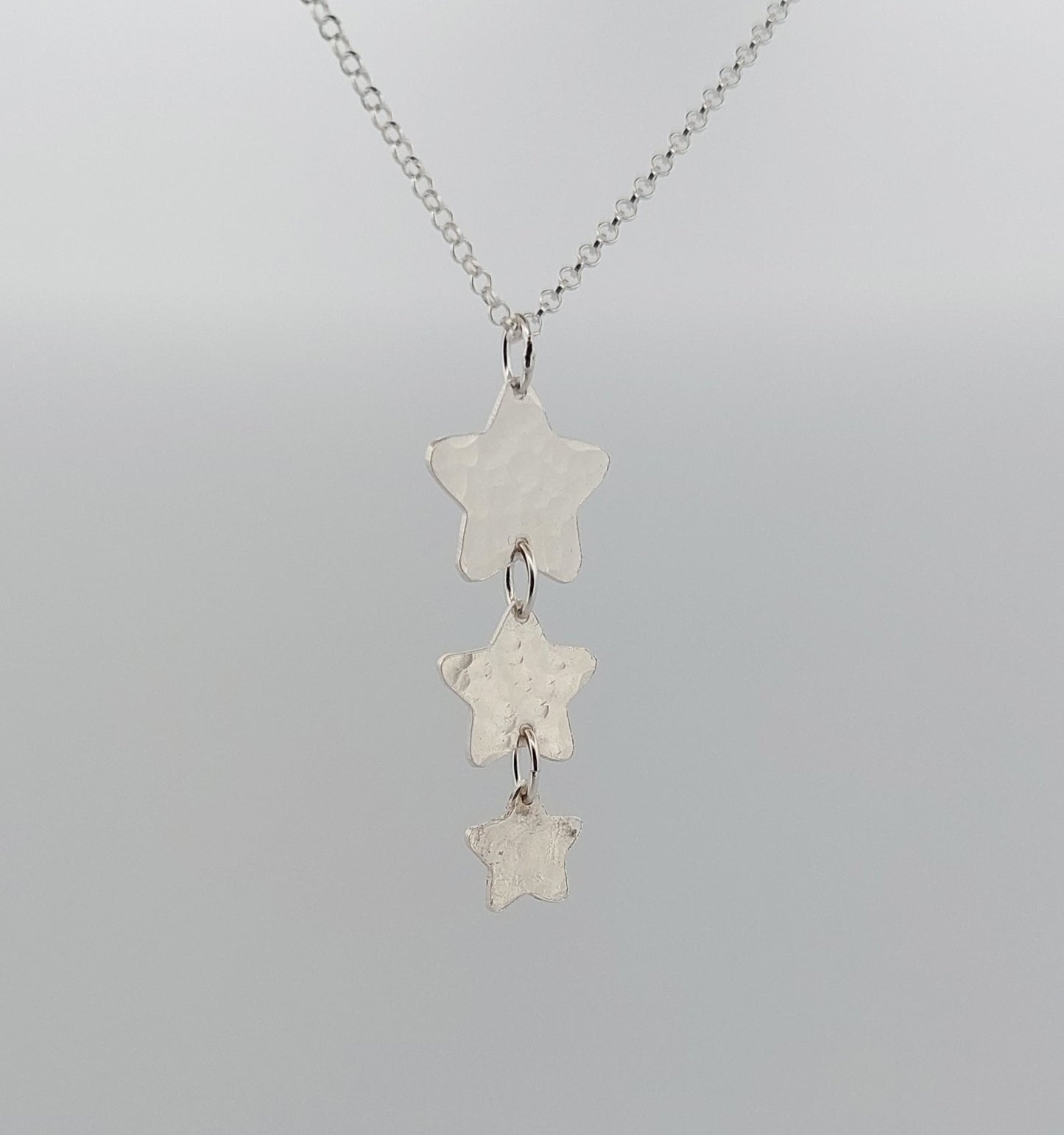 Silver star-shaped pendant necklace on a gray background