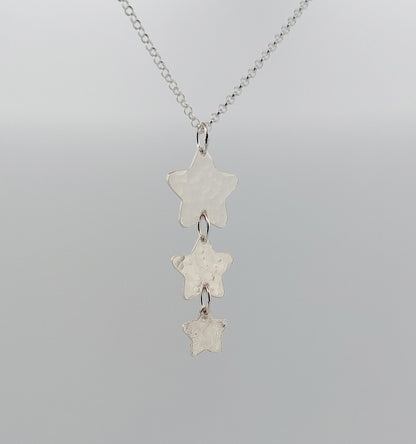 Silver star-shaped pendant necklace on a gray background