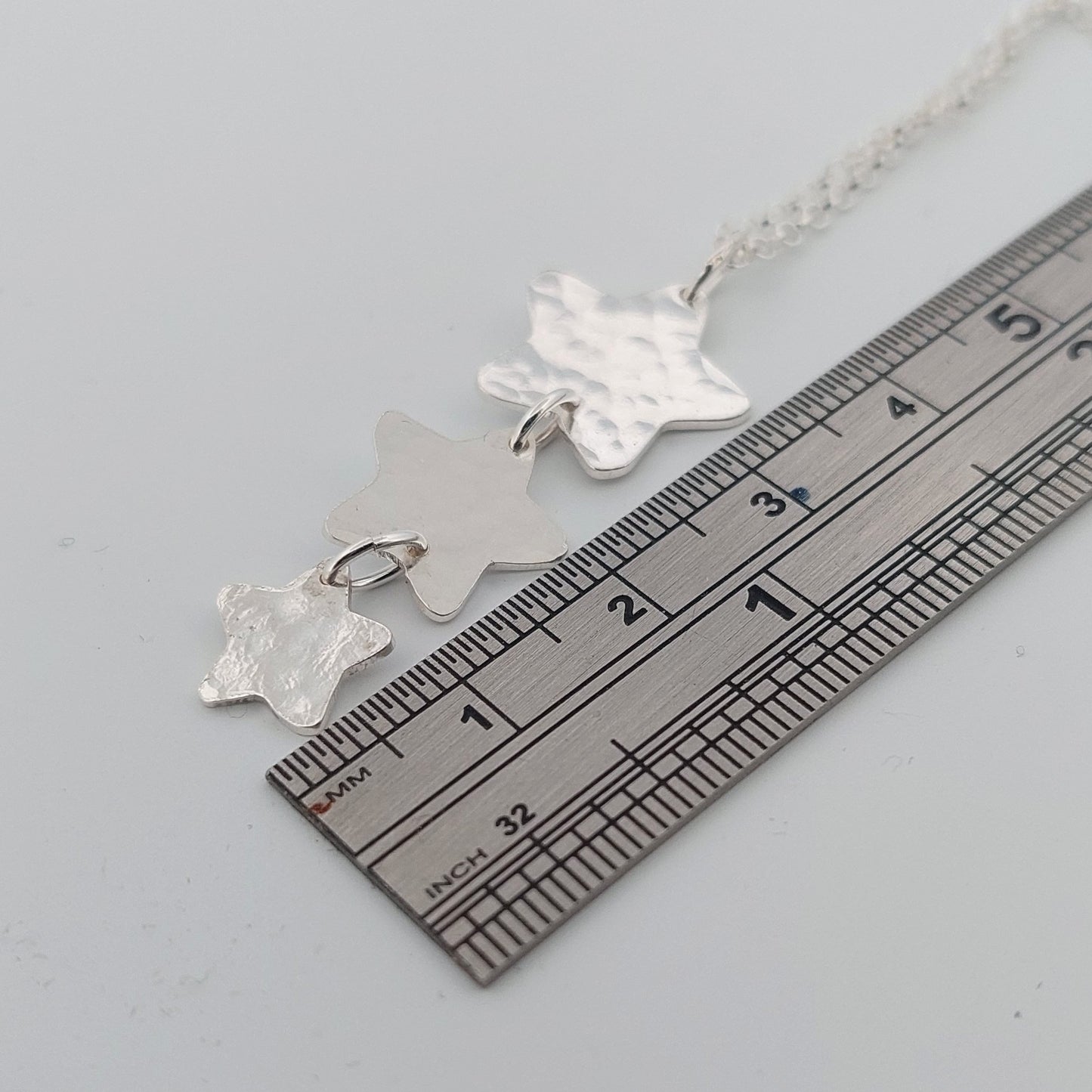 Silver star pendant necklace  on a ruler for scale.
