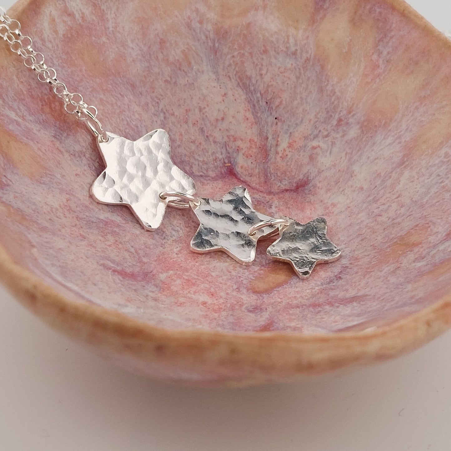 Silver star-shaped necklace set on a pink marbled surface