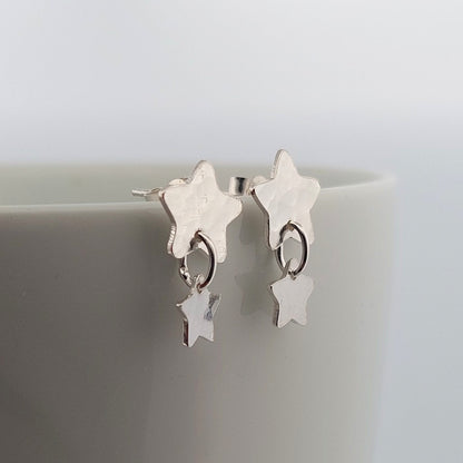 Star-shaped silver earrings on a light gray background