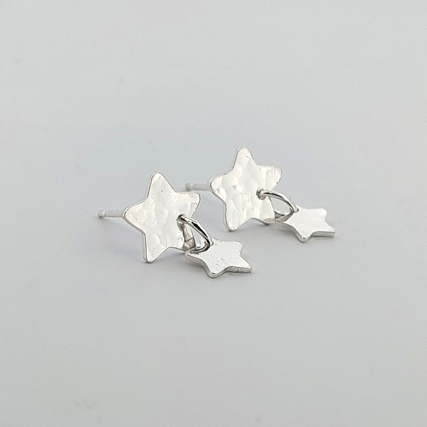 Star-shaped silver earrings on a light gray background