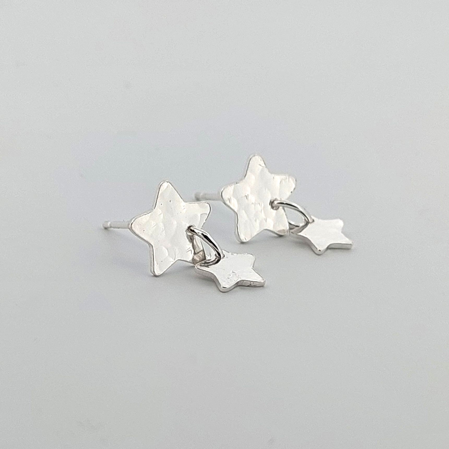 Star-shaped silver earrings on a light gray background