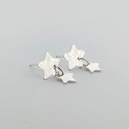 Star-shaped silver earrings on a light gray background