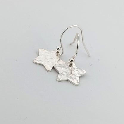 Silver star-shaped earrings on a light gray background