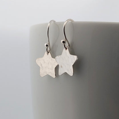 Silver star-shaped earrings on a gray background
