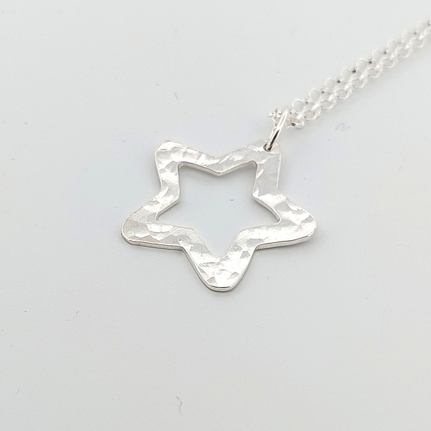 Silver star-shaped pendant on a light gray background