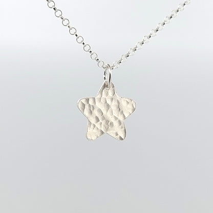 Silver star-shaped pendant on a chain against a light gray background