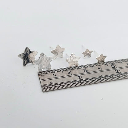 Three sizes of Star-shaped stud earrings with a ruler for scale on a white background