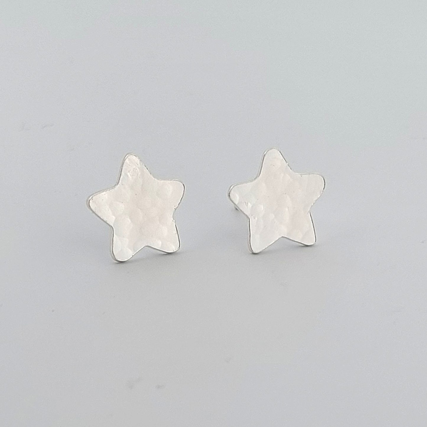 Star-shaped silver earrings on a light gray background