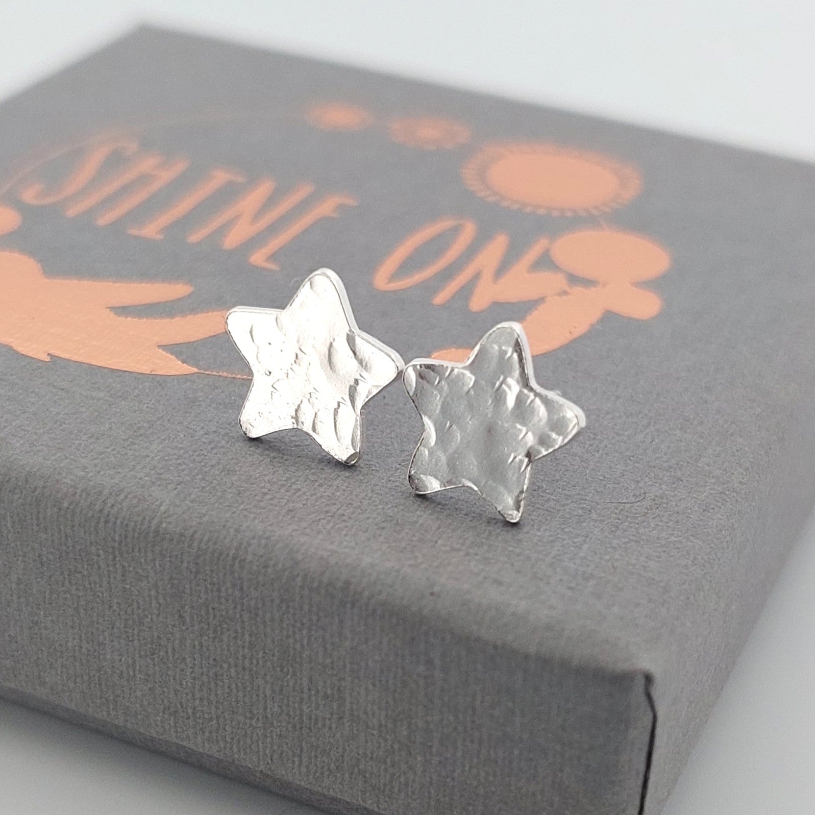 Silver star-shaped earrings on a Shine On gift box