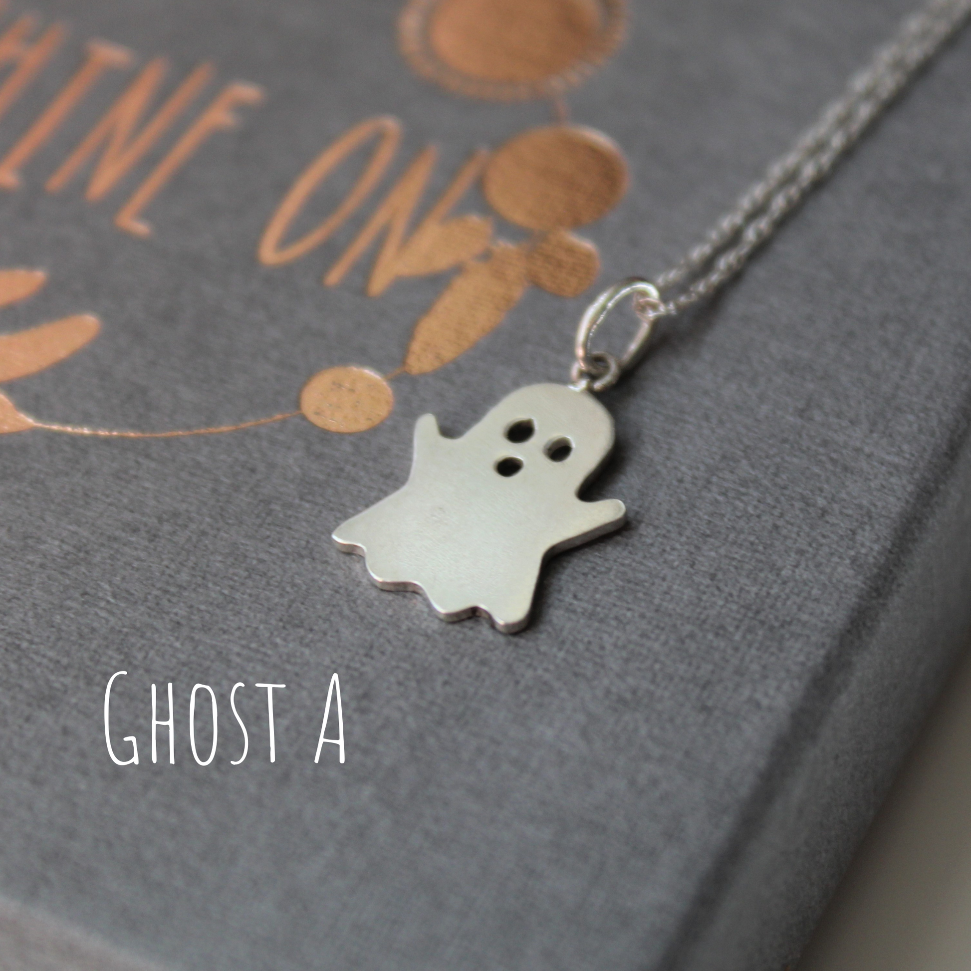 Sterling Silver Ghost Necklace, laying on a grey gift box,  handmade by Shine On