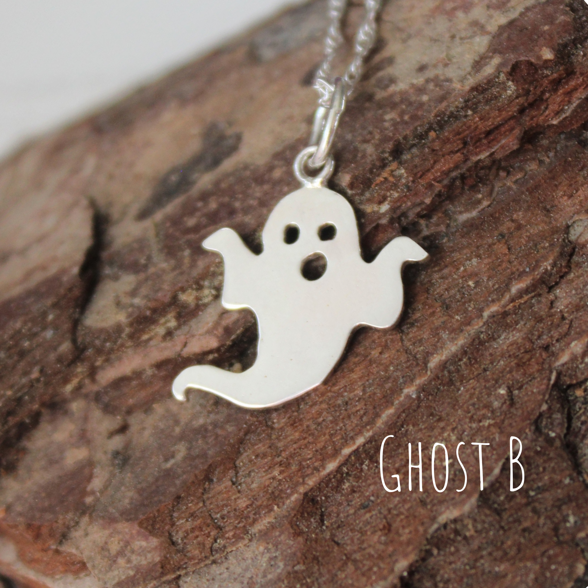 Sterling Silver Ghost Necklace, laying on a piece of wood,  handmade by Shine On